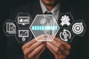 Assessment concept, Businessman hand holding lightbulb with assessment icon on virtual screen. photo