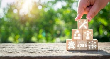 Service concept, Man hand holding wooden block on wooden desk with service icon on virtual screen. photo