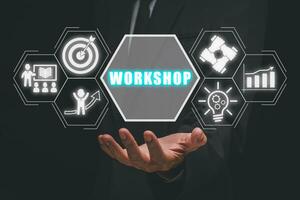 Workshop concept, Businessman hand holding workshop icon on virtual screen. photo