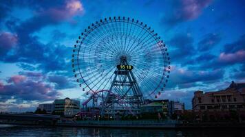 A dusk timelapse of rotating ferris wheel in Yokohama wide shot tilt video