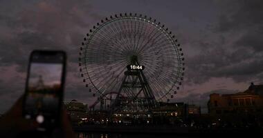 un oscuridad de giratorio ferris rueda disparo por teléfono inteligente en Yokohama video