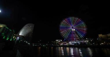 A night rotating ferris wheel at the urban city in Yokohama wide shot video