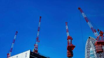 uma espaço de tempo do guindaste às a topo do a construção às a o negócio Cidade dentro Tóquio Largo tiro panning video