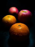 gota de agua sobre la superficie brillante de la frescura de naranja y manzana roja foto