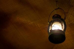 Bright light in an ancient lantern hanging in an old room photo