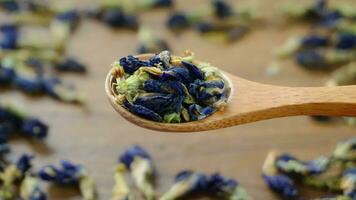 Wooden Spoon with Dried Butterfly Pea Flower Blue Tea Leaves Wood Background. Healthy organic sustainable lifestyle concept. Close up shot, Top view. video