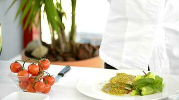 Hands of chef cutting and adding a cherry tomato to a plate video