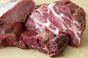 Different types of raw pork meat and beef. Raw meat on wooden table. photo