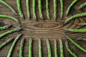 Raw garden asparagus stems. Fresh green spring vegetables on wooden background. photo