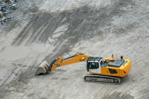 Mining in the granite quarry. Working mining machine - digger. Mining industry. photo