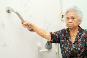 Asian elderly woman use toilet bathroom handle security, healthy strong medical concept. photo