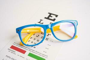 Glasses on eye testing exam chart to check eyesight accuracy of reading. photo