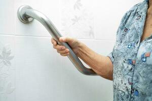 Asian elderly woman use toilet bathroom handle security, healthy strong medical concept. photo