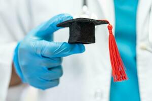 el estudio de un médico asiático aprende con un sombrero de brecha de graduación en la sala del hospital, un concepto de medicina inteligente y brillante. foto