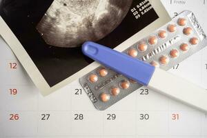 Pregnancy test and birth control pills with ultrasound scan of baby uterus, contraception health and medicine. photo