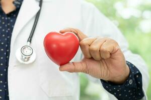 médico sosteniendo un corazón rojo en la sala del hospital, concepto médico fuerte y saludable. foto