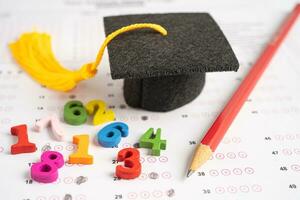 Graduation gap hat and pencil on answer sheet paper, Education study testing learning teach concept. photo