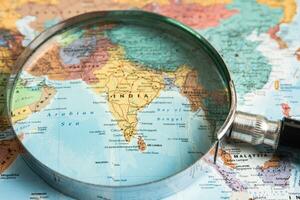 Bangkok, Thailand  January 20, 2022 India, Magnifying glass close up with colorful world map, travel, geography, tourism and exploration concept. photo