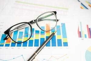 Eyeglass on chart graph paper. Finance, account, statistic, investment data economy, stock exchange business. photo