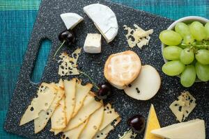 Cold appetizer. Cold cuts. Cheese on cutting board isolated on blue background, top view photo