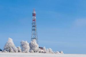 Transmission tower in winter, Telecommunications tower with cellular antenna and satellite dish photo