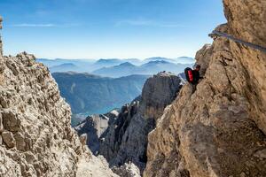 Male mountain climber on a Via Ferrata in breathtaking landscape of Dolomites Mountains in Italy. Travel adventure concept. photo