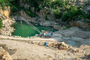 Mining in the granite quarry. Working mining machine - old crane. Mining industry. photo