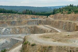 Opencast mining quarry with machinery. Quarrying of stones for construction works. Mining industry in quarry. photo