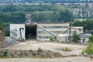 Big silos, belt conveyors and mining equipment in a quarry. Quarrying of stones for construction works. Mining industry in quarry. photo