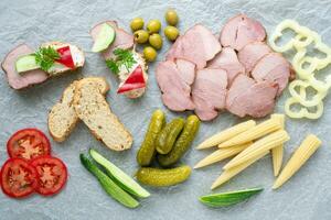 Cold appetizer. Cold cuts. Different snacks on a white crumpled paper, from above. photo