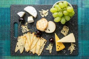 Cold appetizer. Cold cuts. Cheese on cutting board isolated on blue background, top view photo
