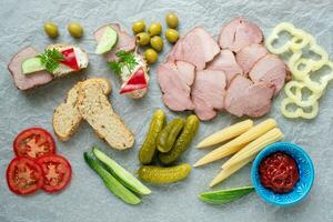 Cold appetizer. Cold cuts. Different snacks on a white crumpled paper, from above. photo