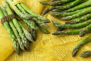 Bunches of asparagus tied with twine on a burlap background. Asparagus officinalis. photo