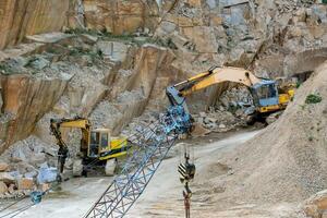 Mining in the granite quarry. Working mining machine - old crane and digger. Mining industry. photo