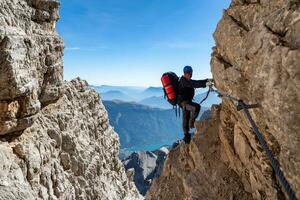masculino montaña trepador en un vía vía ferrata en asombroso paisaje de dolomitas montañas en Italia. viaje aventuras concepto. foto