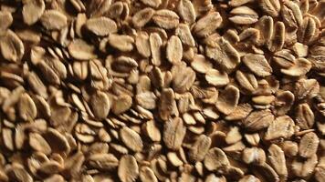 Oat Flakes Background Slowly Rotating Counter-Clockwise - Top View, Low Key Light. Scattered Dry Oat Flakes. Healthy Breakfast and Diet Eating Ingredients - Angular Rotation Left video