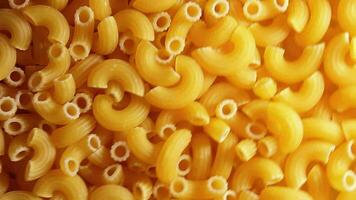 ongekookt chifferi rigati pasta - top visie, laag sleutel. dik en ongezond voedsel. klassiek droog macaroni, roterend achtergrond. Italiaans cultuur en keuken. rauw gouden pasta structuur - Rechtsaf hoekig omwenteling video