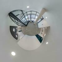 abstractly twisted into a spherical 360 panorama interior of a modern office with a hall staircase and panoramic windows photo