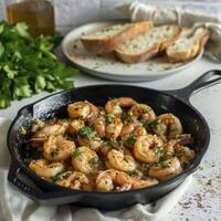 AI generated A cast iron skillet with garlic shrimp, on a white countertop. Behind the skillet is a plate with a portion of shrimp and bread photo