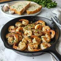 AI generated A cast iron skillet with garlic shrimp, on a white countertop. Behind the skillet is a plate with a portion of shrimp and bread photo