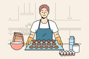 Man baker prepares oatmeal cookies or gingerbread while standing near kitchen table with ingredients. Baker guy dressed in apron and gloves proudly demonstrates dessert ready for baking. vector