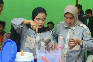 two women wearing headscarves were selling ice cream with their hands pouring ice into packets photo