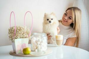 Beautiful young woman with Pomeranian spitz dog and cup of coffee at home. High quality photo