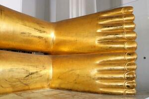 Close up of reclining Buddha statue's feet, gold color and scratch on surface, Thailand. photo