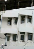 Front of old white building, closed window with tint, geometric shape level design, Thailand. photo