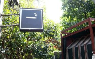 Tobacco sign on black square shape light box in natural environment, symbol for smoking area , Thailand. photo