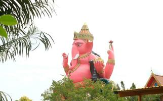 rosado ganesha hormigón estatua sentado postura y cielo fondo, junto a vista. foto