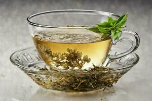 AI generated Hot tea with beautiful tea leaves is poured into a glass cup on a saucer. Cup with black tea and herbal leaves on a gray background. photo