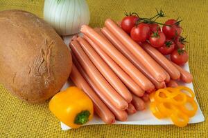 Raw frankfurter sausages and bread on white plate photo