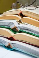 Pile of open books and reading glasses photo